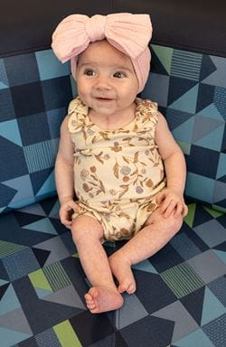 Smiling infant girl with big, pink bow.