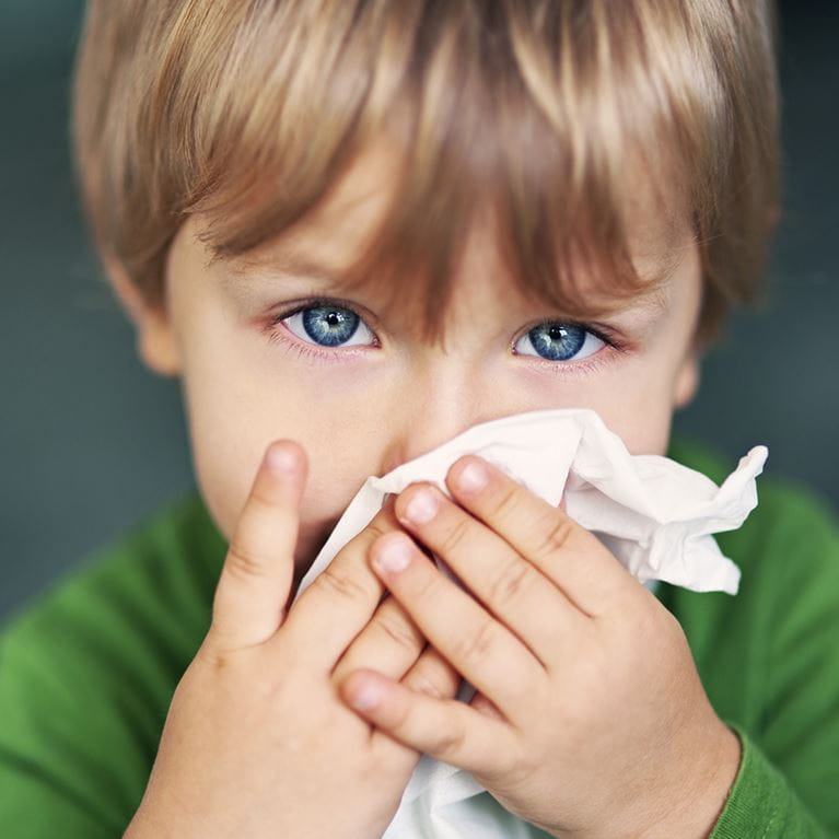 Boy with tissue wiping nose