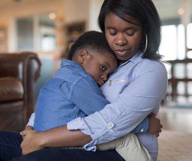 Mom in blue shirt holding young son in her arms.