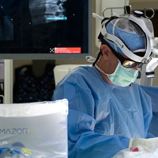 Doctor in operating room using Mazor robot.