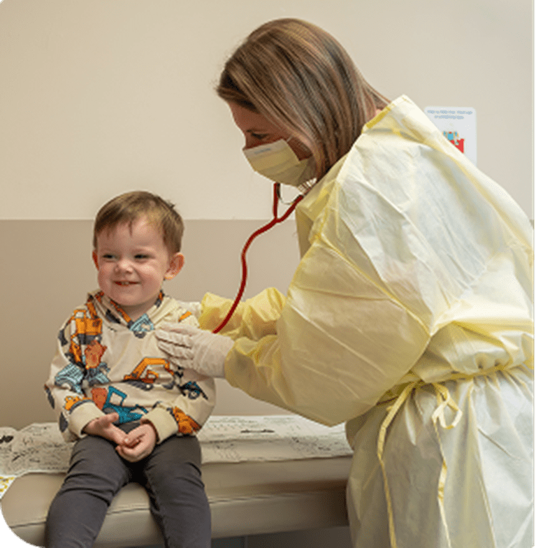 Toddler boy in sitting in clinic with nurse.