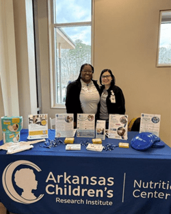 ACNC team members standing behind display table.