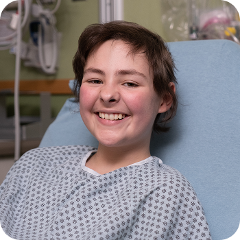 Teenage patient in hospital gown with a big smile.